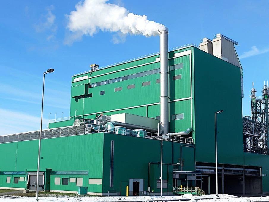 A large green pre-engineered multi-storey building featuring a prominent chimney