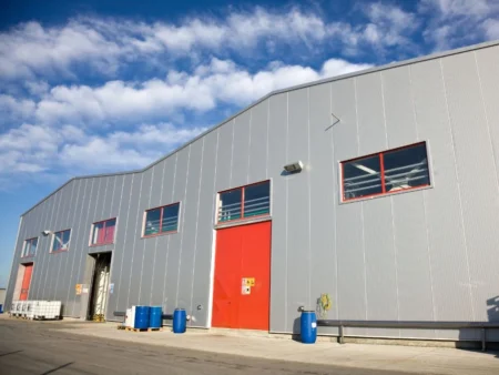 A Large Industrial Building Featuring Red Doors Representing A Pre Engineered Building Manufacturer