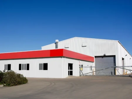 A Large Industrial Building With A Red Roof Highlighting The Work Of A Pre Engineered Building Manufacturer