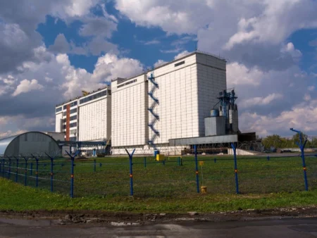 A Multi Storey Industrial Building With A Fence Set Against A Bright Blue Sky