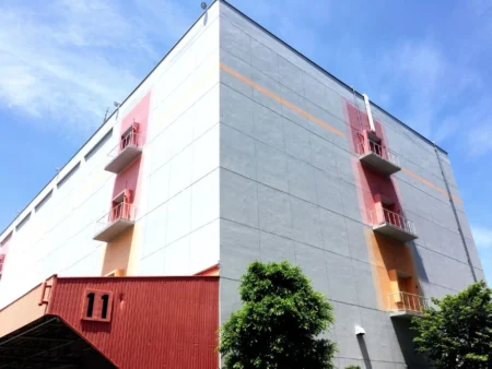 A Multi Storey Pre Engineered Building Featuring A Striking Red And Orange Facade With A Matching Door