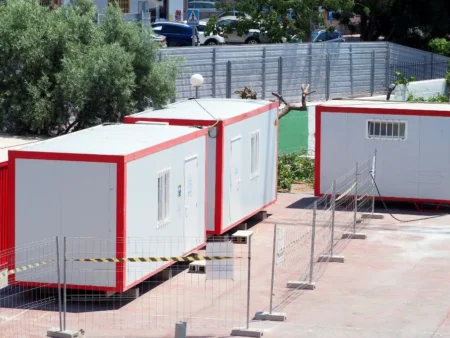 A Parking Lot Filled With Small White And Red Insulated Cabins Representing Prefabricated Porta Cabins From A Manufacturer